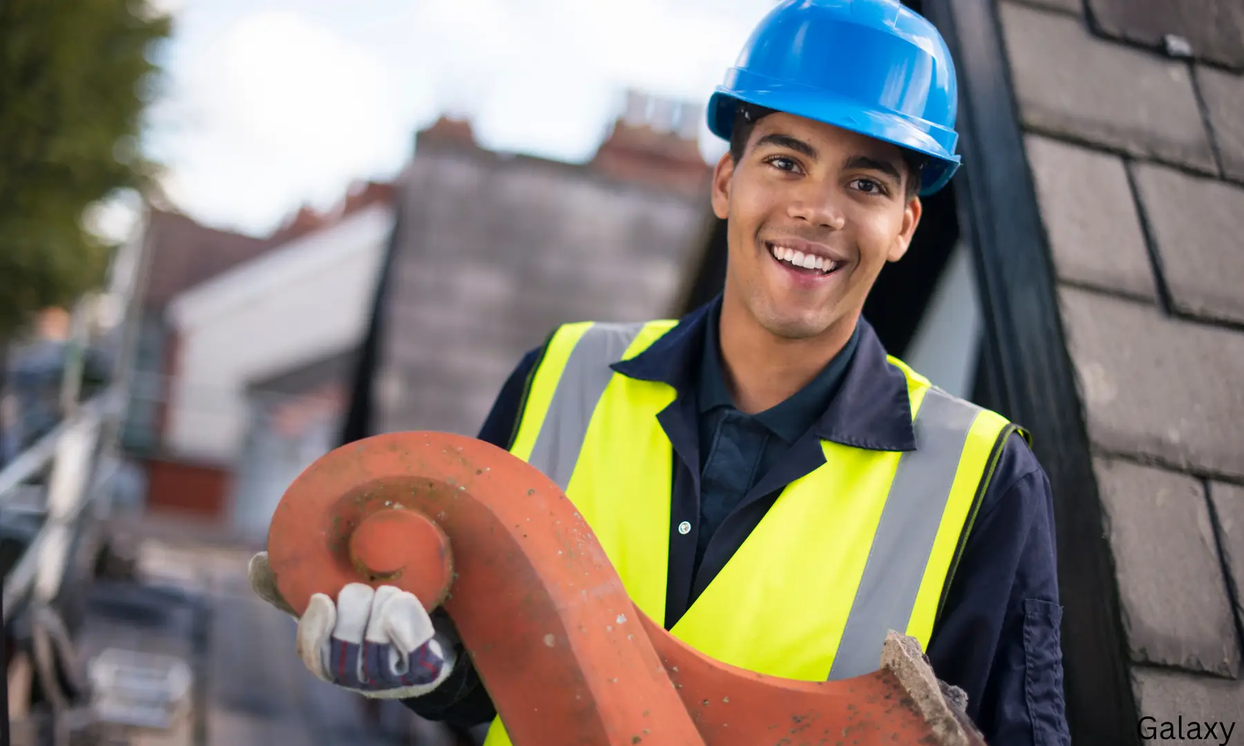 Roofer holding a ridge tile beside a tiled roof